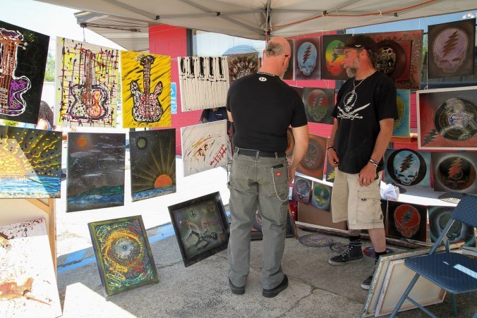 Visitors browsing original prints at a festival artist booth