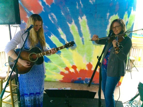 Two musicians performing in front of a brightly painted mural
